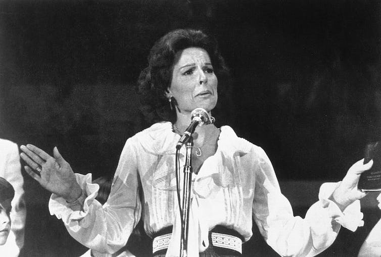 Fotografía en blanco y negro de una mujer hablando ante un micrófono.