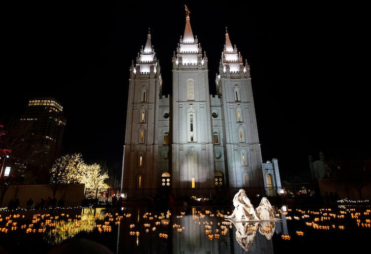 Un edificio de iglesia de aspecto grandioso con torres altas iluminadas por la noche.
